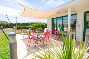 een patio met rode stoelen en tafels onder een luifel bij ibis Perpignan Nord Rivesaltes in Rivesaltes