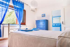 a bedroom with a bed with blue curtains and a window at Il carrubo B&b in Maratea