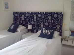 ウェストン・スーパー・メアにあるルウィンスダール ロッジのベッドルーム1室(ベッド2台、ヘッドボードに蝶が飾られたベッド付)