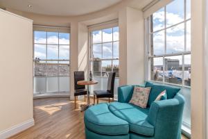 sala de estar con sofá azul y ventanas grandes en Victoria Court Suites - Aberdeen en Aberdeen