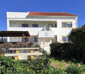 een wit gebouw met een bord ervoor bij Apartamentos na Quinta Altavista do Carvalhal in Zambujeira do Mar