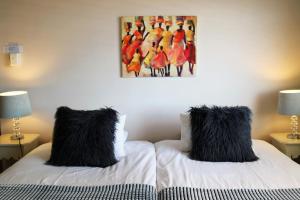 Duas almofadas pretas em duas camas num quarto em Dolphin Inn Guesthouse na Cidade do Cabo