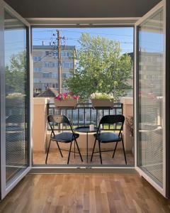 2 Stühle und ein Tisch auf einem Balkon mit Fenstern in der Unterkunft Danubiana Apartments in Kladovo