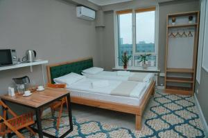 Halal Apart Hotel Almaty في ألماتي: غرفة نوم بسرير كبير وطاولة