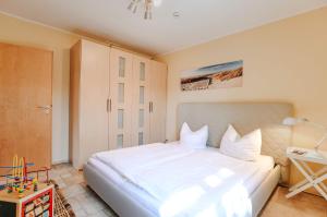 una camera da letto con un grande letto bianco e un tavolo di Ferienwohnung Am Leuchtfeuer EG a Wustrow