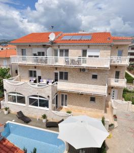 a building with a swimming pool and an umbrella at Apartment House Jerko in Kaštela