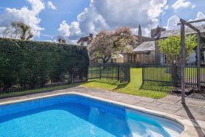ein Schwimmbad in einem Garten neben einem Zaun in der Unterkunft Gothic House Cottage in Clare