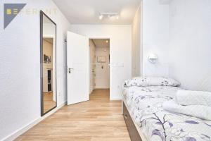 - une chambre blanche avec un lit et un miroir dans l'établissement Beferent San Juan Pueblo II, à San Juan de Alicante
