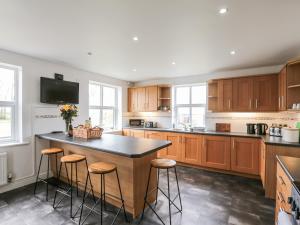 a kitchen with wooden cabinets and a island with stools at West Border Farm in Wigton