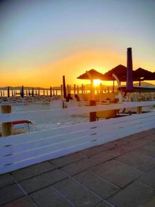 アルゲーロにあるB&B Fraluciaの白いベンチが夕日を眺めながらビーチに座る