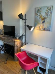 - un bureau avec une chaise rouge et un bureau avec une lampe dans l'établissement Chaleureux studio * Neuf * Hypercentre * Wifi *, à Orléans