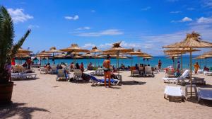 een groep mensen op een strand met stoelen en parasols bij Апартаменти Свети Георги - Saint George Apartments in Kavarna