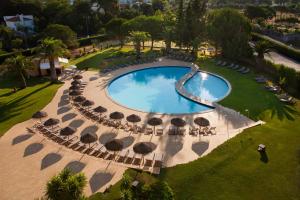 Una vista aérea de una piscina con sombrillas y sillas. en Evora Hotel, en Évora