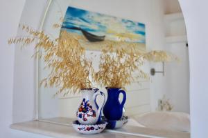 two blue and white vases sitting on a shelf with plants at Aegeo Inn in Antiparos