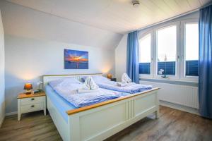 Schlafzimmer mit einem Bett mit blauer Bettwäsche und einem Fenster in der Unterkunft Ferienhaus Daheim in Borkum