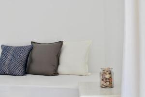a white couch with pillows and a vase on a table at Aegeo Inn in Antiparos