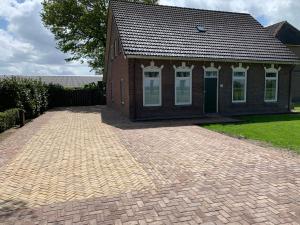 a brick house with a brick driveway in front of it at Vakantiehuis de Turfvaart in Wachtum