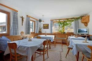 un restaurante con mesas y sillas blancas y ventanas en Oberachenhof, en Ellmau