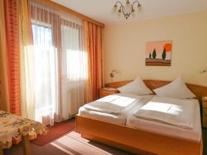 a bedroom with a bed and a large window at Strandpension Liane in Sankt Kanzian