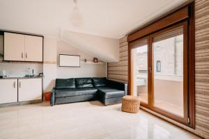 a living room with a black leather couch and a kitchen at Apartamento La Iglesia in Caldas de Reis