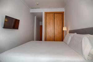 a bedroom with a bed and a dresser at Sercotel Tribuna Málaga in Málaga