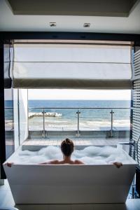 a person in a bath tub with a view of the ocean at Sanatorium Uzdrowiskowe Bałtyk in Kołobrzeg