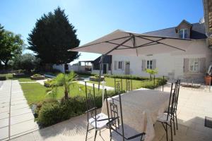 un patio con mesa y sombrilla en Gîte LES DOUCESHEURES- 110m²--3 chambres-6 pers en Betz-le-Château