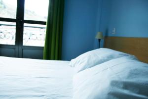 a bedroom with a white bed and a window at La Refierta in Cangas del Narcea