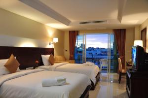 a hotel room with two beds and a television at August Suites in Pattaya