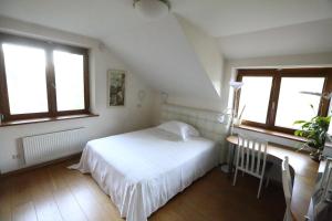 a bedroom with a white bed and two windows at Magical Place in Vilnius