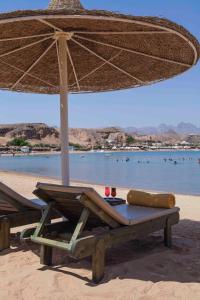 a picnic table with an umbrella on the beach at Xperience St. George Sharm El Sheikh in Sharm El Sheikh