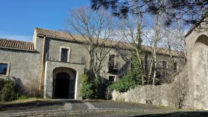 un antiguo edificio de piedra con puerta y entrada en Etna Holiday Home, en Nicolosi