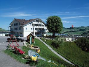duży biały budynek na wzgórzu obok ulicy w obiekcie Panorama Hotel Freudenberg w mieście Appenzell