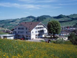 Ein weißes Haus auf einem Hügel mit einem Blumenfeld in der Unterkunft Panorama Hotel Freudenberg in Appenzell