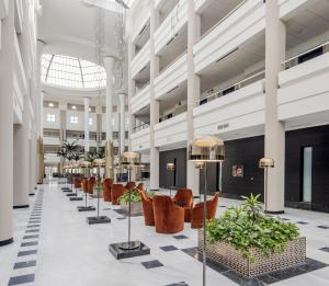 a lobby with chairs and plants in a building at Ilunion Alcora Sevilla in San Juan de Aznalfarache