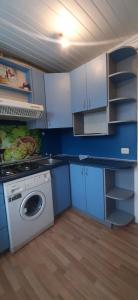 une cuisine avec un lave-linge et des armoires bleues dans l'établissement Vienibas 38a, à Daugavpils
