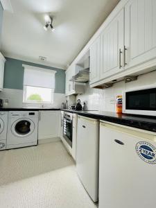 a kitchen with white cabinets and a washer and dryer at Modern 2 bed Apartment Near City Centre in Glasgow