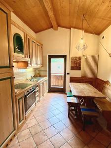 a kitchen with a wooden table and a wooden ceiling at Cèsa MeSa in Canazei