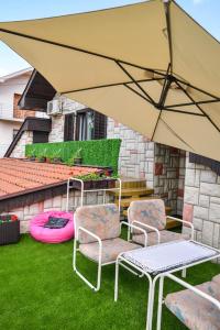 a patio with two chairs and an umbrella at Apartman Domacinstvo La ViE na selu in Niška Banja