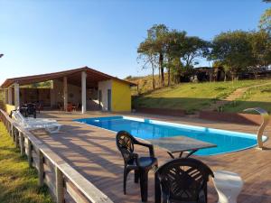 um deque com uma mesa e cadeiras ao lado de uma piscina em Pousada Capão Fôrro em São Roque de Minas