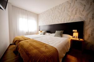 Un dormitorio con una cama grande y una ventana en Cantares-NOJA ROOMS, en O Pedrouzo