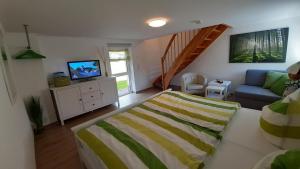 a bedroom with a bed and a couch and a television at Christianshof Insel Usedom in Stoben