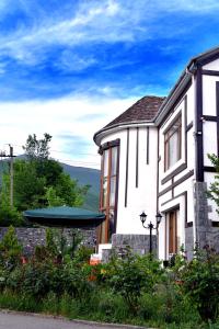 a white house with a green umbrella in the yard at Ansera 55 Hotel Sheki in Sheki