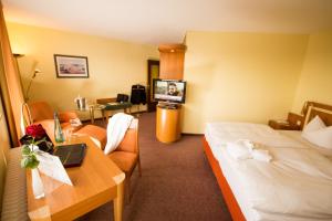 a hotel room with a bed and a table with a laptop at Ringhotel Parkhotel Witten in Witten
