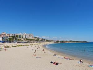 a beach with people laying on the sand and the water at Apartament Elizabet in Tarragona