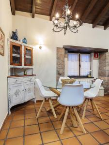 a dining room with a glass table and white chairs at El Llagar de Naveda in Naveda