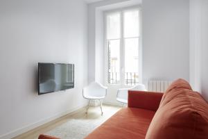 sala de estar con sofá y TV en la pared en Etxaide - Basque Stay, en San Sebastián