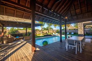 an outdoor deck with a table and chairs and a pool at Mythic Suites & Villas in Grand Gaube