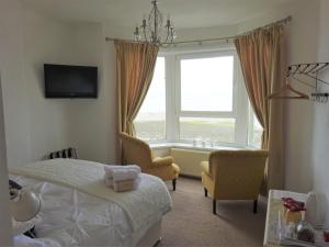 a bedroom with a bed and two chairs and a window at Shipping Lanes Hotel in Morecambe