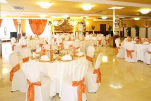 um salão de banquetes com mesas e cadeiras brancas em Hotel La Nava em Iznalloz